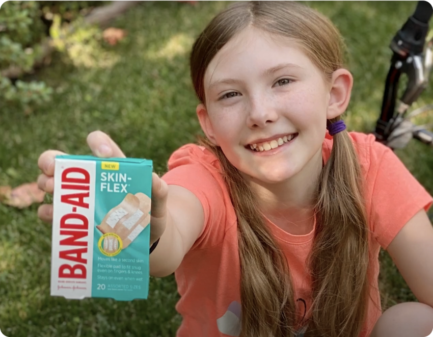 Girl holding BAND-AID® Skin-Flex® adhesive bandages