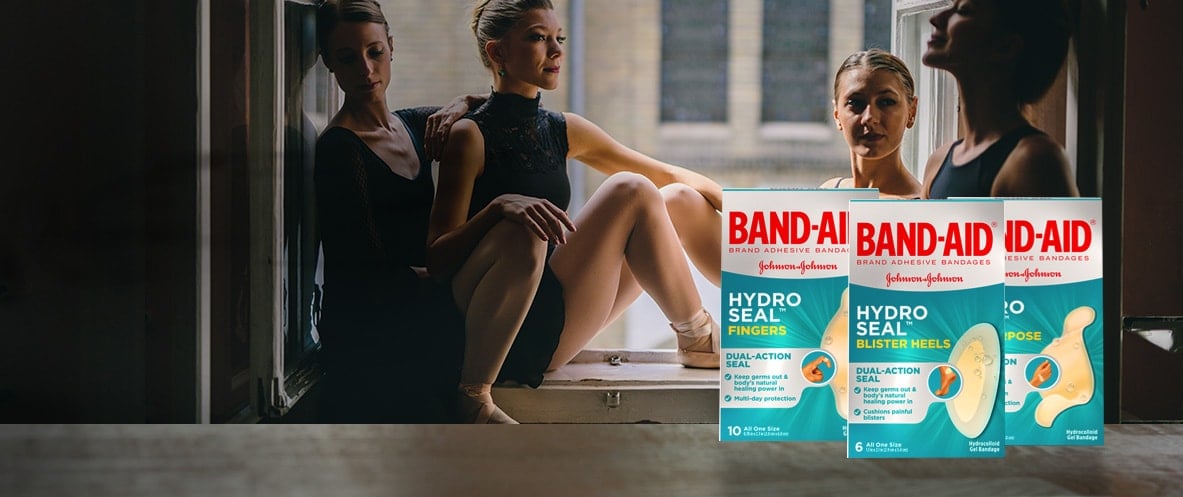 Boxes of BAND-AID® Brand HYDRO SEAL® gel bandages in front of a group of ballerinas