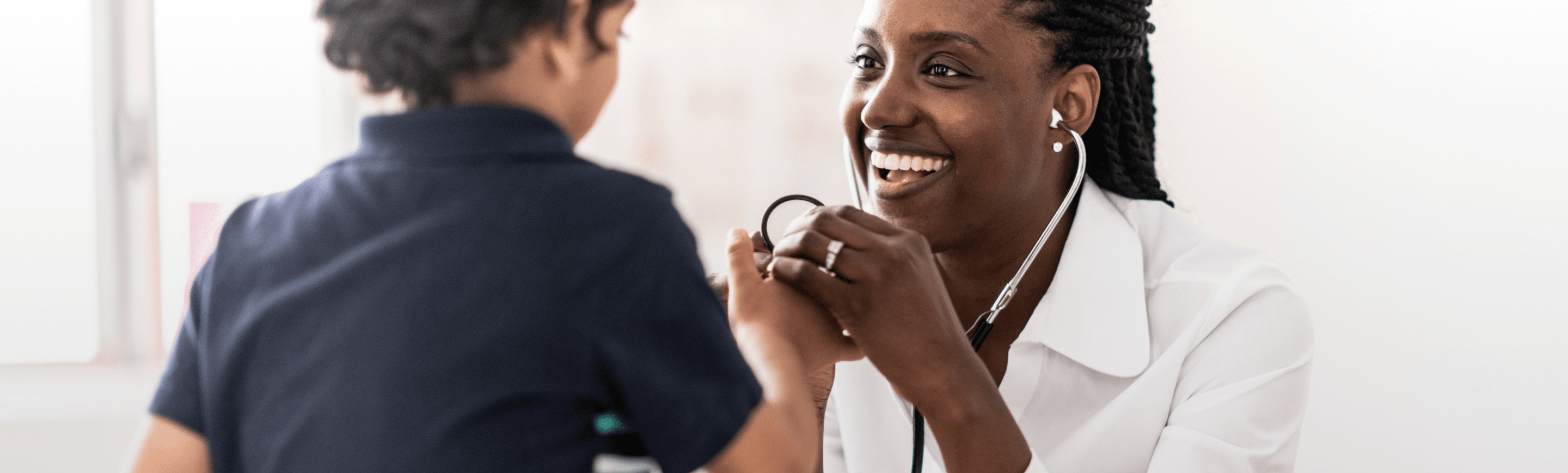 Female doctor smiling at a child as she checks their blood pressure.