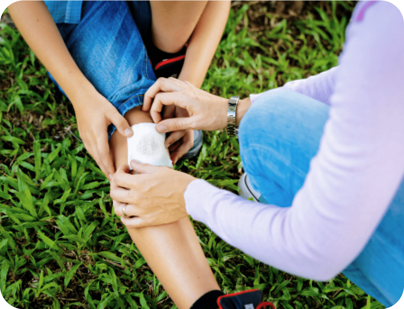 Adult placing adhesive bandage on child to protect a scraped knee.