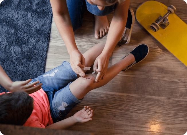 Person helping to bandage a child’s wounded knee.