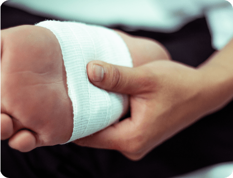 Person wrapping a wound on their foot with gauze.