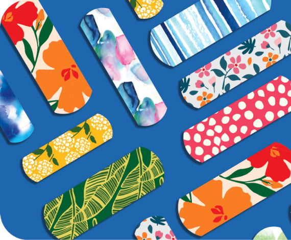 Assortment of BAND-AID® Brand limited-edition collection of cute & fun bandages laid out on a blue background